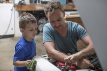 Figlio aiutare padre in garage a casa a lavorare sulla macchina — Foto stock