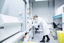 Jeune femme scientifique travaillant dans un laboratoire biologique utilisant un microscope — Photo de stock
