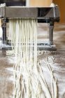 Making linguine in pasta machine — Stock Photo