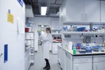 Científica joven que trabaja en laboratorio biológico inspeccionando muestras - foto de stock