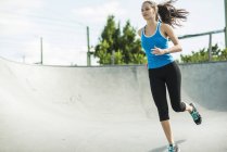 Спортивная молодая женщина бегает в скейт-парке — стоковое фото