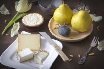 Variedad de quesos, peras, higos y piñones sobre superficie de madera marrón - foto de stock