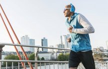Germania, Francoforte, uomo con le cuffie che fa jogging sul ponte — Foto stock