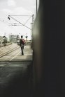 Young man with skateboard standing on railway platform — Stock Photo