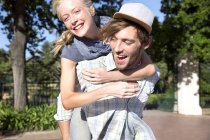 Jovem feliz carregando namorada piggyback — Fotografia de Stock