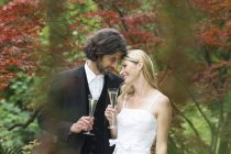 Felice sposa e sposo con bicchieri di champagne in giardino — Foto stock