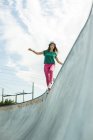 Jovem mulher equilibrando em uma parede em um parque de skate — Fotografia de Stock