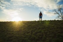 Jovem olhando para o sol nascente — Fotografia de Stock