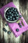 Bleuets dans un bol en zinc sur bois foncé avec serviette rose — Photo de stock