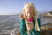 Mujer joven sonriente con teléfono celular en la costa - foto de stock
