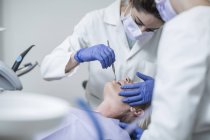Dentista femenina examinando paciente con espejo bucal - foto de stock