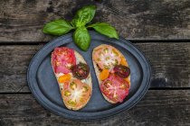 Tomato bread with Heirloom tomatoes and basil on a wooden table — Stock Photo