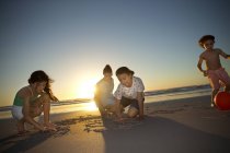 Famiglia sulla spiaggia al tramonto disegno in sabbia — Foto stock
