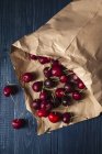 Fresh cherries in brown paper on grey wooden surface — Stock Photo