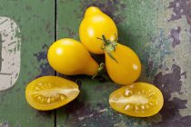 Halved and whole yellow pear tomatoes on green shabby wood — Stock Photo
