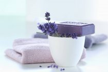 Fiore di lavanda con sapone e asciugamano lavanda su sfondo bianco — Foto stock