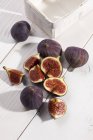 Halved and whole figs on white wooden table — Stock Photo