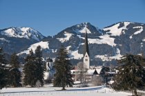Germany, Allgaeu, Fischen with Hornergruppe mountains in background in winter sunny day — Stock Photo