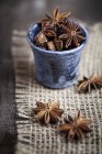 Star anise in tiny blue cup on burlap, studio shot — Stock Photo