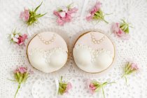 Bride and bride cupcakes for same-sex wedding on doily with flowers — Stock Photo
