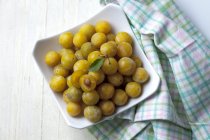 Fresh Mirabelles in bowl on white wooden table — Stock Photo