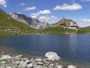 Австрия, Каринтия, Карнийские Альпы, Волейское озеро с хижиной и военным мемориалом — стоковое фото