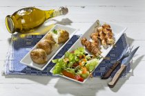 Hühnerfleischstäbchen mit Bratkartoffeln und gemischtem Salat vor weißem Holzhintergrund — Stockfoto