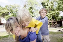 Madre sorridente che gioca con i bambini nel parco giochi — Foto stock