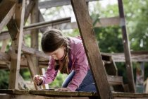 Menina segurando prego na escada de madeira no playground — Fotografia de Stock