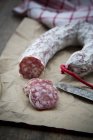 Close-up of partly sliced Italian salami on parchment — Stock Photo