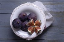 Fresh whole and halved Figs in a bowl on wood — Stock Photo