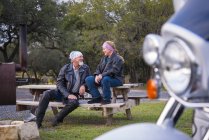 Dois motociclistas fazendo uma pausa no banco de madeira — Fotografia de Stock