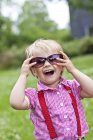Petite fille portant des lunettes de soleil debout dans la nature — Photo de stock