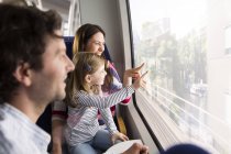 Glückliche Familie in einem Zug, der ins Fenster zeigt — Stockfoto