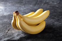 Куча свежих бананов на черной ткани — стоковое фото