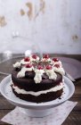 Chocolate cake filled and garnished with cherries and cream on cake stand — Stock Photo