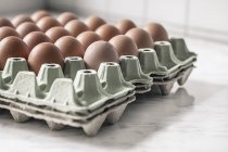 Carton palette with brown eggs on white marble — Stock Photo