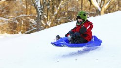 Маленький хлопчик на санчатах на схилі у зимовий період — стокове фото