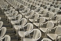 Linhas de cadeiras de plástico branco à luz do sol — Fotografia de Stock