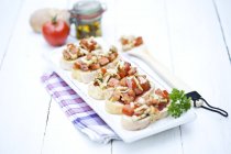 Plate of bruschetta with tomatoes, white shimeji mushrooms, herbs and olive oil on wooden table, close up — Stock Photo