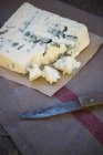Pezzo di gorgonzola su pergamena con coltello — Foto stock