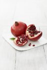 Whole and broken Pomegranates on white wooden table — Stock Photo