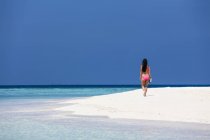 Maldivas, Jovem mulher de biquíni andando na praia — Fotografia de Stock