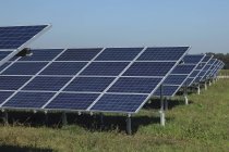 Paneles solares sobre hierba contra cielo - foto de stock