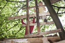 Хлопчики грають на ігровому майданчику в дерев'яному будинку, дивлячись вниз — стокове фото