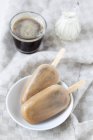 Lecca ghiaccio cappuccino su piatto con bicchiere di caffè su tessuto — Foto stock