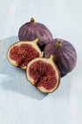 Sliced and whole figs on white wooden surface — Stock Photo