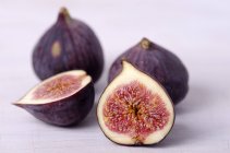Fresh whole and halved figs on white surface — Stock Photo