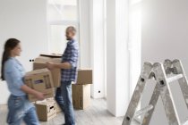 Young carrying cardboard boxes in new home — Stock Photo