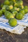 Close-up of Brussels sprouts on wooden surface with cloth — Stock Photo